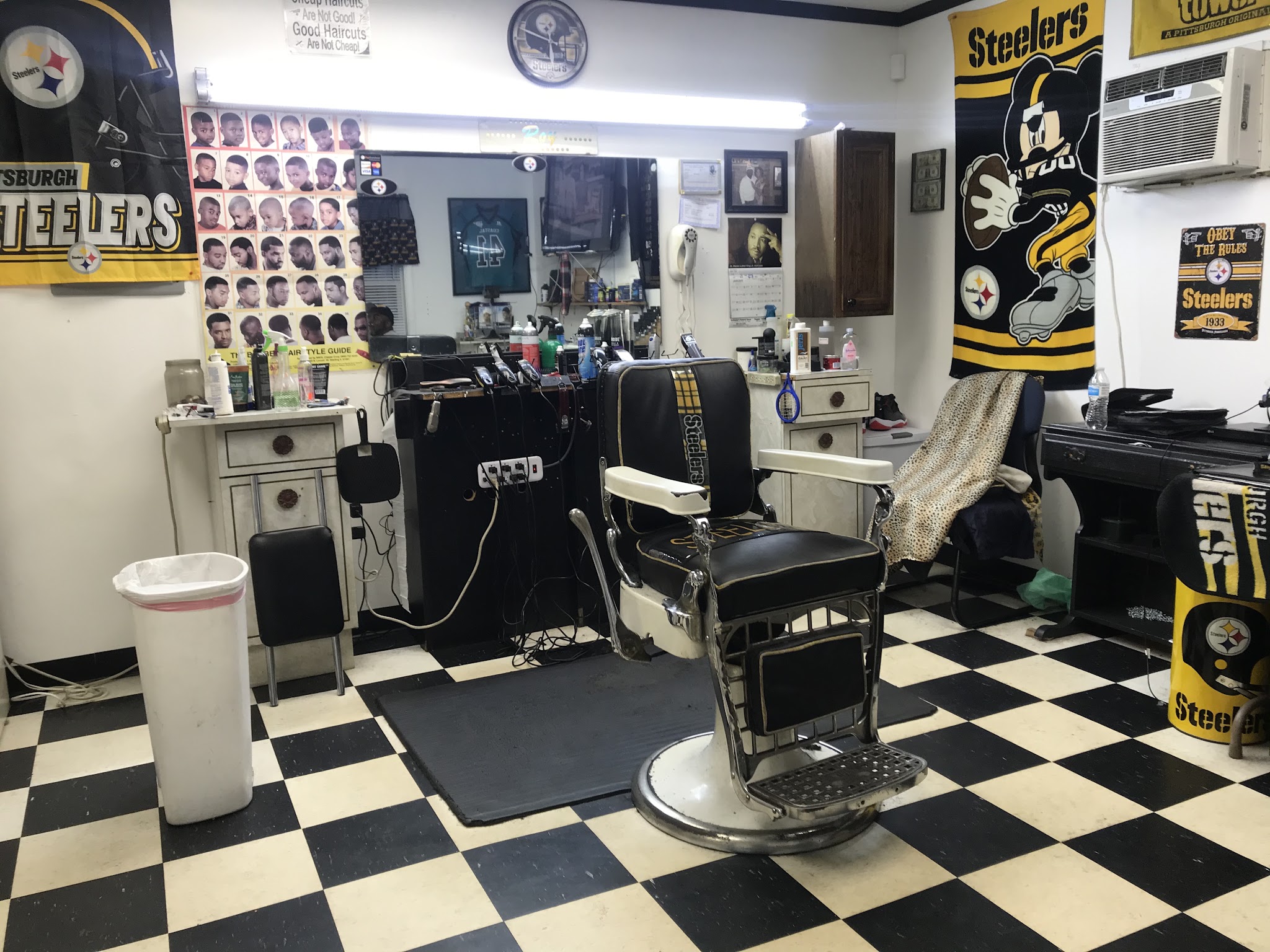 Inside the shop: a vintage chrome barber chair, Steelers banners and a checkerboard floor